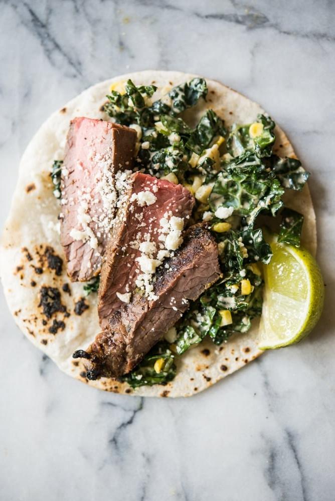Carne Asada Tacos Rezept mit Adobo-Limetten-Marinade 2 Rindfleisch Carne Asada auf Grünkohl und Krautsalat in einer Maistortilla auf einem Marmorbrett