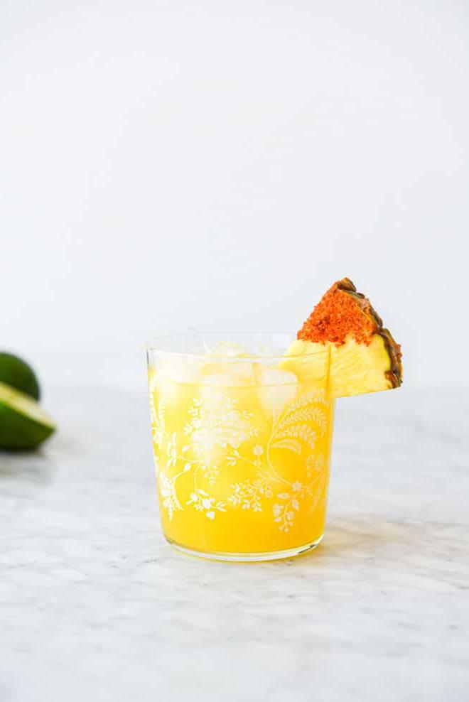 Die beste Ananas-Margarita (2 Varianten!) 2 Ein Margarita-Glas mit einem Ananas Margarita auf Eis, garniert mit einem in Chili-Salz getauchten Ananas-Keil.