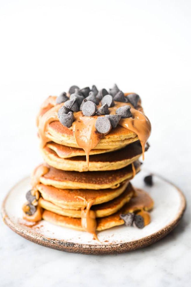 Wie man Protein-Pfannkuchen zubereitet 2 Ein Stapel Protein-Pancakes, garniert mit Erdnussbutter und Schokoladenstückchen.