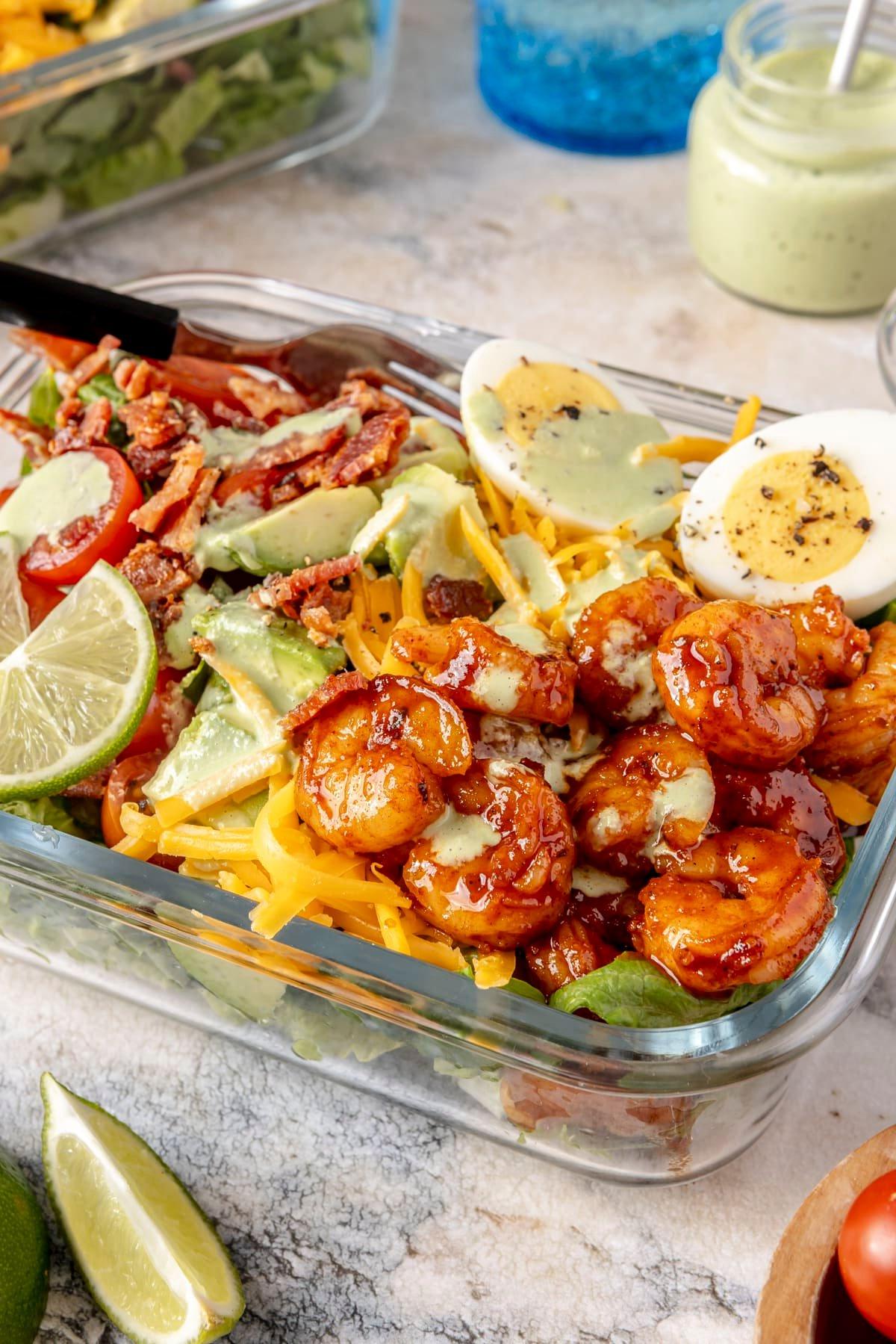Scharfer Honig-Garnelen-Cobb-Salat 2 Ein Glas-Meal-Prep-Behälter gefüllt mit scharfem Garnelen-Cobb-Salat.