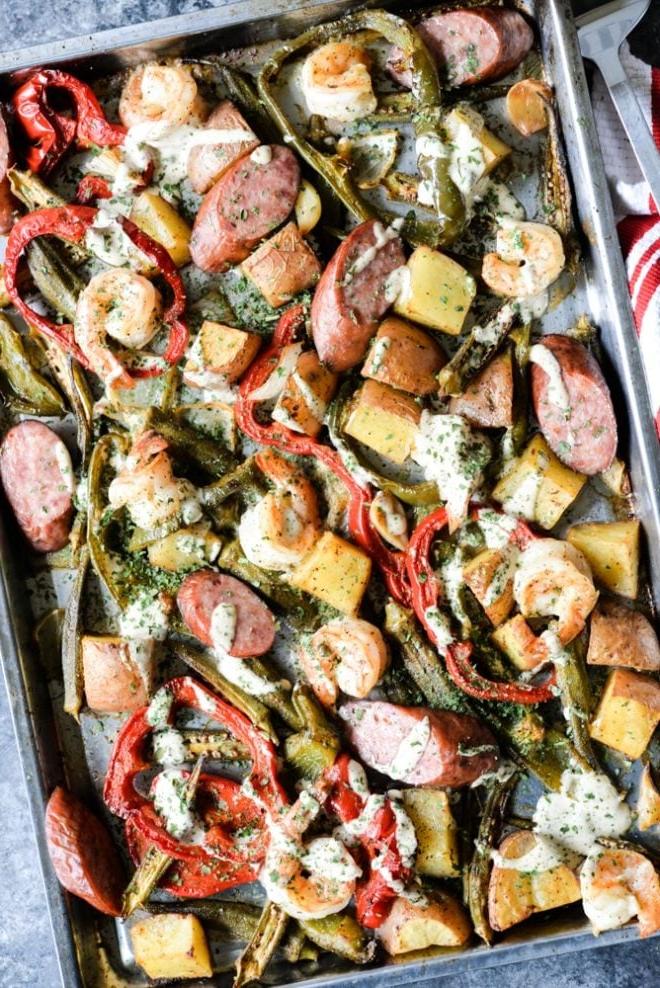 Cajun Garnelen vom Backblech 2 Ofenblech mit Wurst, Garnelen, Kartoffeln, Spargel und roten Paprika, übergossen mit einer cremigen Soße – Draufsicht