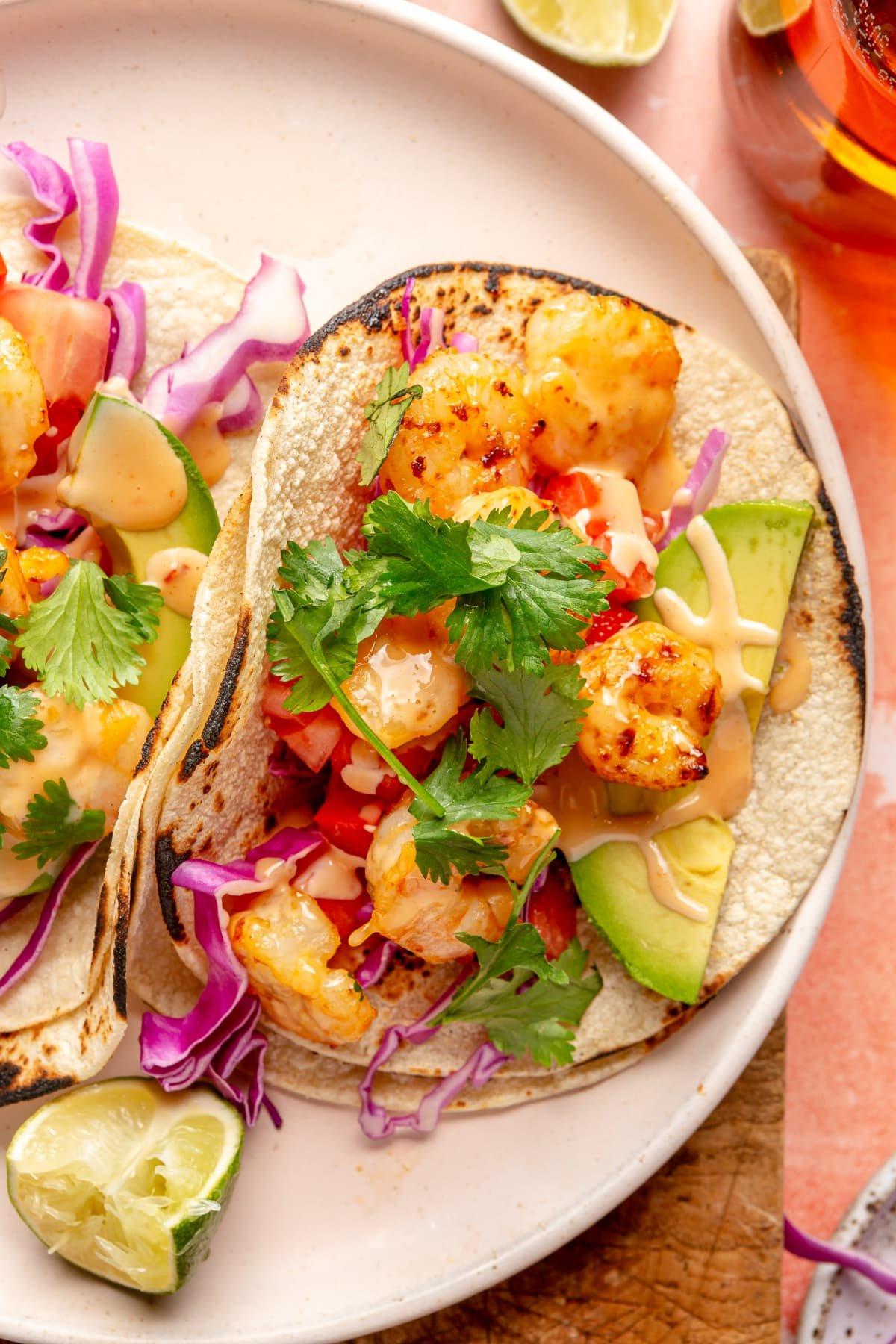 Scharfe Bang Bang Garnelen Tacos 2 Cremefarbene Platte mit kunstvoll angerichteten scharfen Bang Bang Garnelen Tacos.
