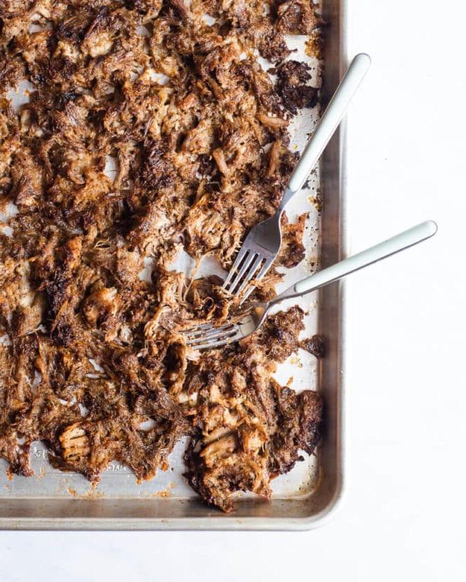 Knusprige Schweinefleisch-Carnitas auf einem Backblech mit zwei Gabeln daneben