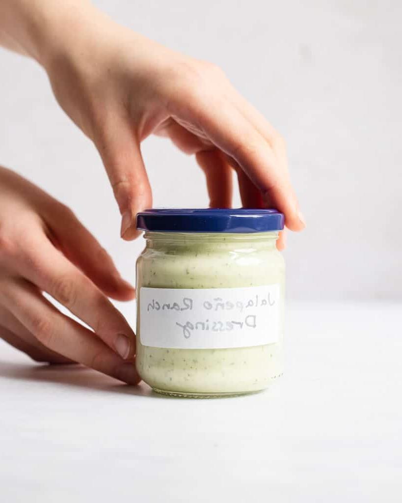 Jalapeño-Ranch-Dressing 2 Eine Person hält ein kleines, beschriftetes Glas mit selbstgemachtem Jalapeño Ranch Dressing in den Händen.