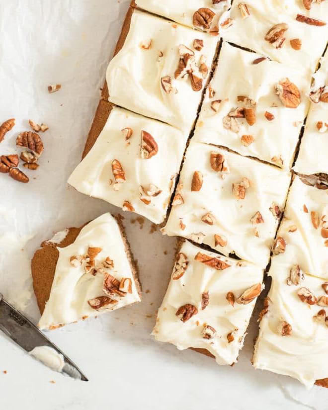 Ein glasierter Gewürzkuchen mit Pekannüssen belegt, in 12 Portionen geschnitten auf Backpapier