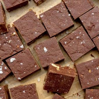 Kleine Quadrate aus Schokoladenfudge auf einem braunen Stück Backpapier.