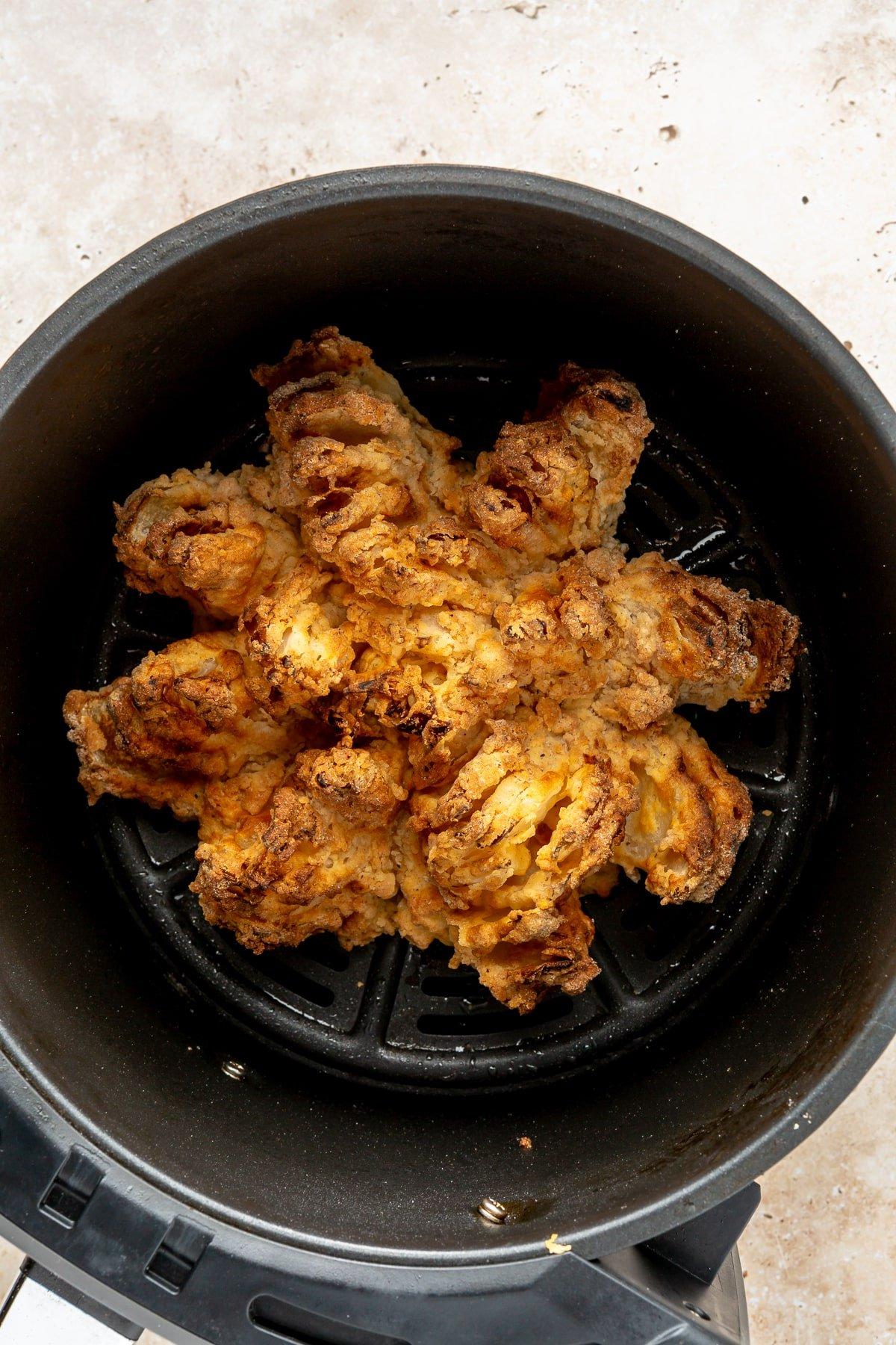 Heißluftfritteuse Blühende Zwiebel 11 Schritt 8: Die frisch zubereitete Blühende Zwiebel wird appetitlich auf einem Teller angerichtet, daneben eine Schale mit der cremigen Dip-Soße, bereit zum Genießen.