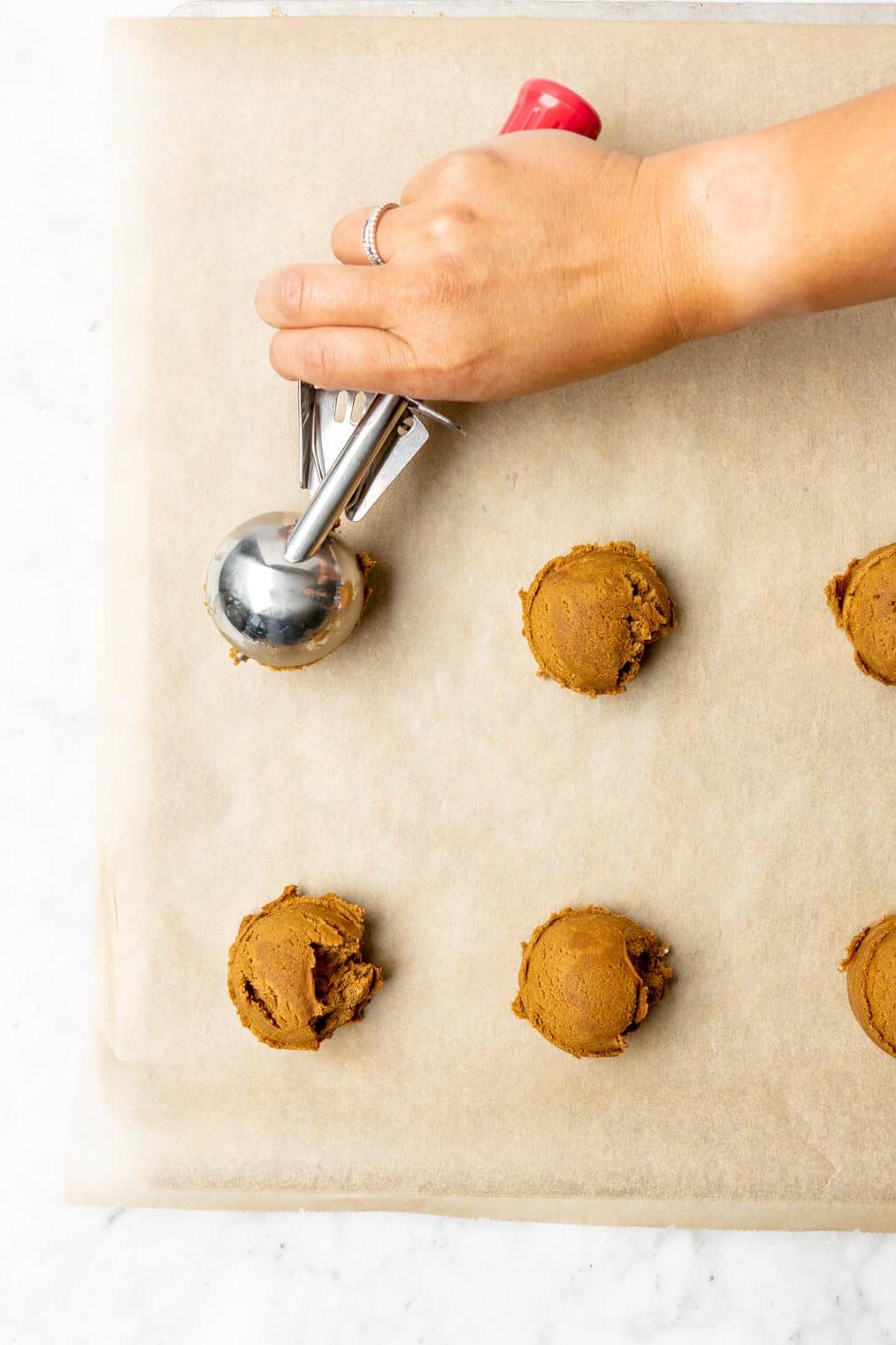 220817_Rum Raisin Cookies-36 Draufsicht auf Kekse, die auf ein mit Backpapier ausgelegtes Backblech geschöpft werden.