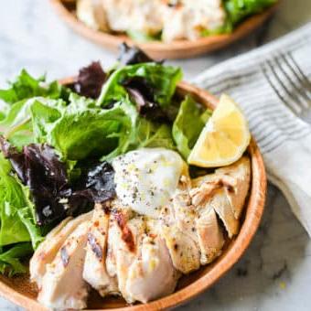 Zitronenpfeffer-Joghurt-Grillhähnchen 6 Geschnittenes Zitronen-Pfeffer-Joghurt-Hähnchen vom Grill, serviert in einer Schale auf gemischtem Salat