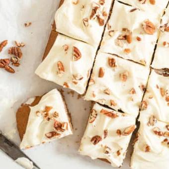 Ein glasierter Gewürzkuchen mit Pekannüssen belegt, in 12 Portionen geschnitten auf Backpapier