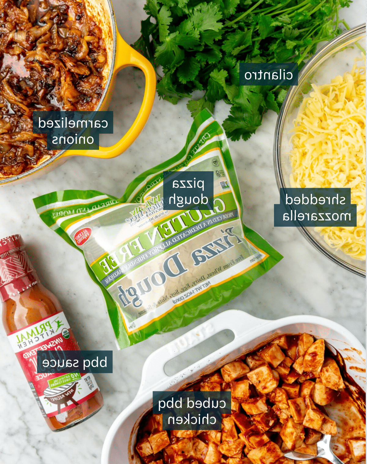 Zutaten für BBQ Hähnchen Pizza auf einer Marmorarbeitsplatte.