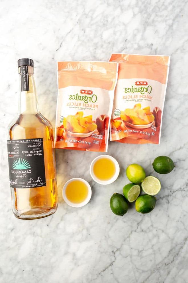 Das beste Pfirsich-Margarita-Rezept 3 Zutaten für gefrorene Pfirsich Margarita auf einer Marmoroberfläche.