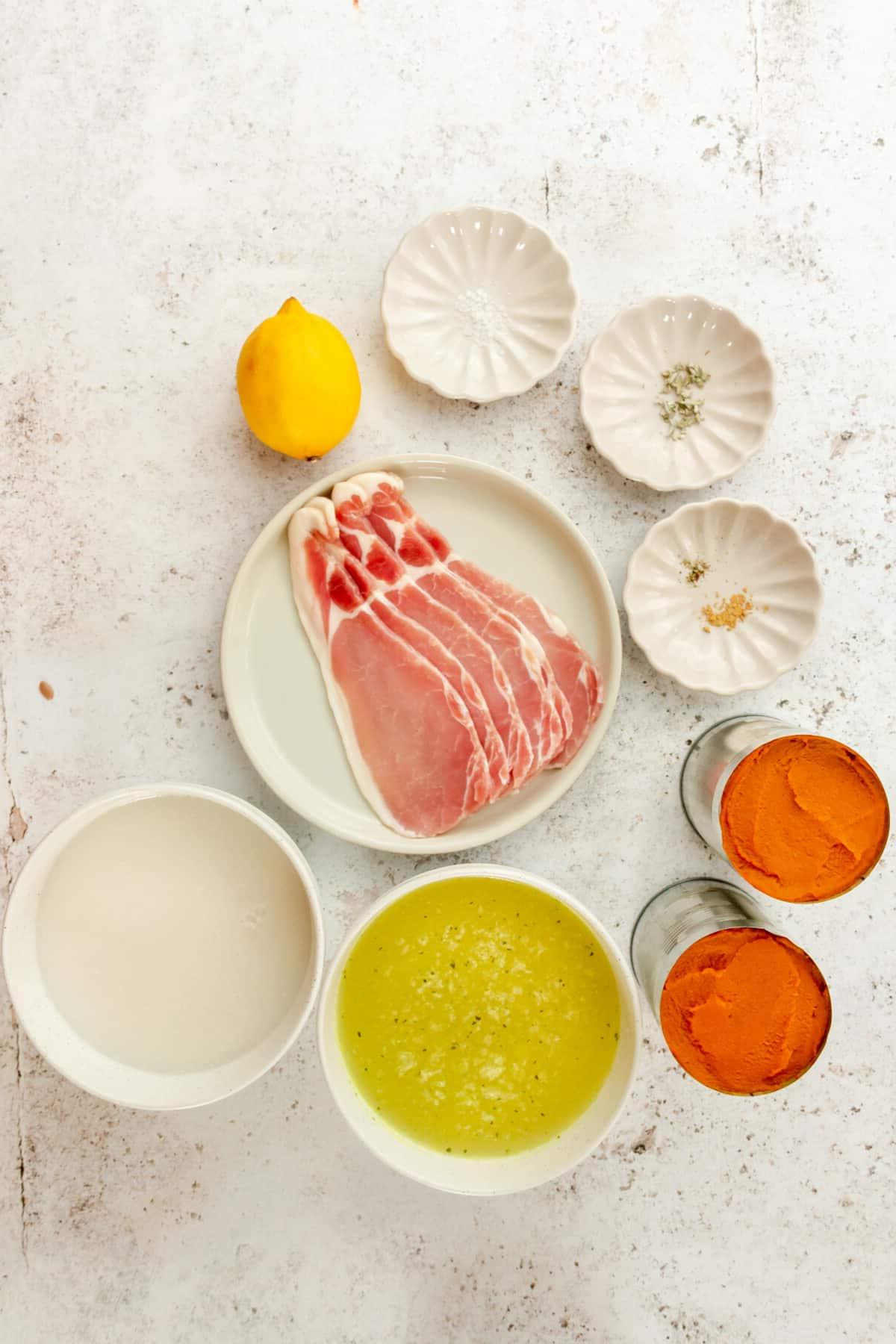 Zutaten für einfache Kürbissuppe in verschiedenen Schalen und Tellern auf hellem Untergrund.
