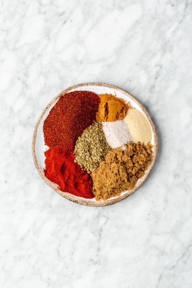 Beste Trockenmarinade für Schweinefilet 3 Draufsicht auf die Zutaten für das Dry Rub auf einer unregelmäßig runden Schale. Die Schale steht auf einer grau-weißen Marmoroberfläche.