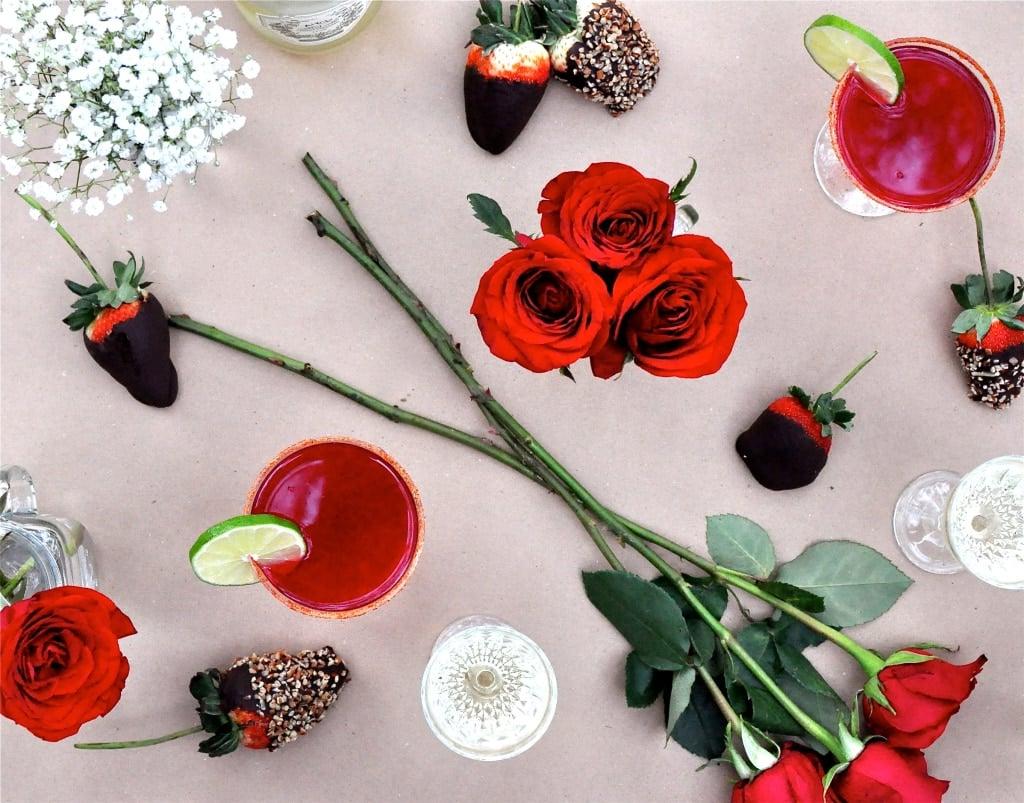Zutaten für den Granatapfel Martini: Wodka, Granatapfelsaft, Limetten und Chili-Pulver auf einem Tisch ausgebreitet.