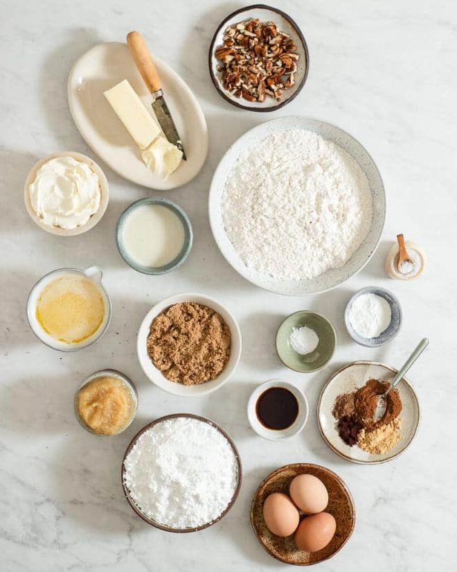 Alle Zutaten für Gewürzkuchen in verschiedenen Schüsseln auf einer Marmoroberfläche