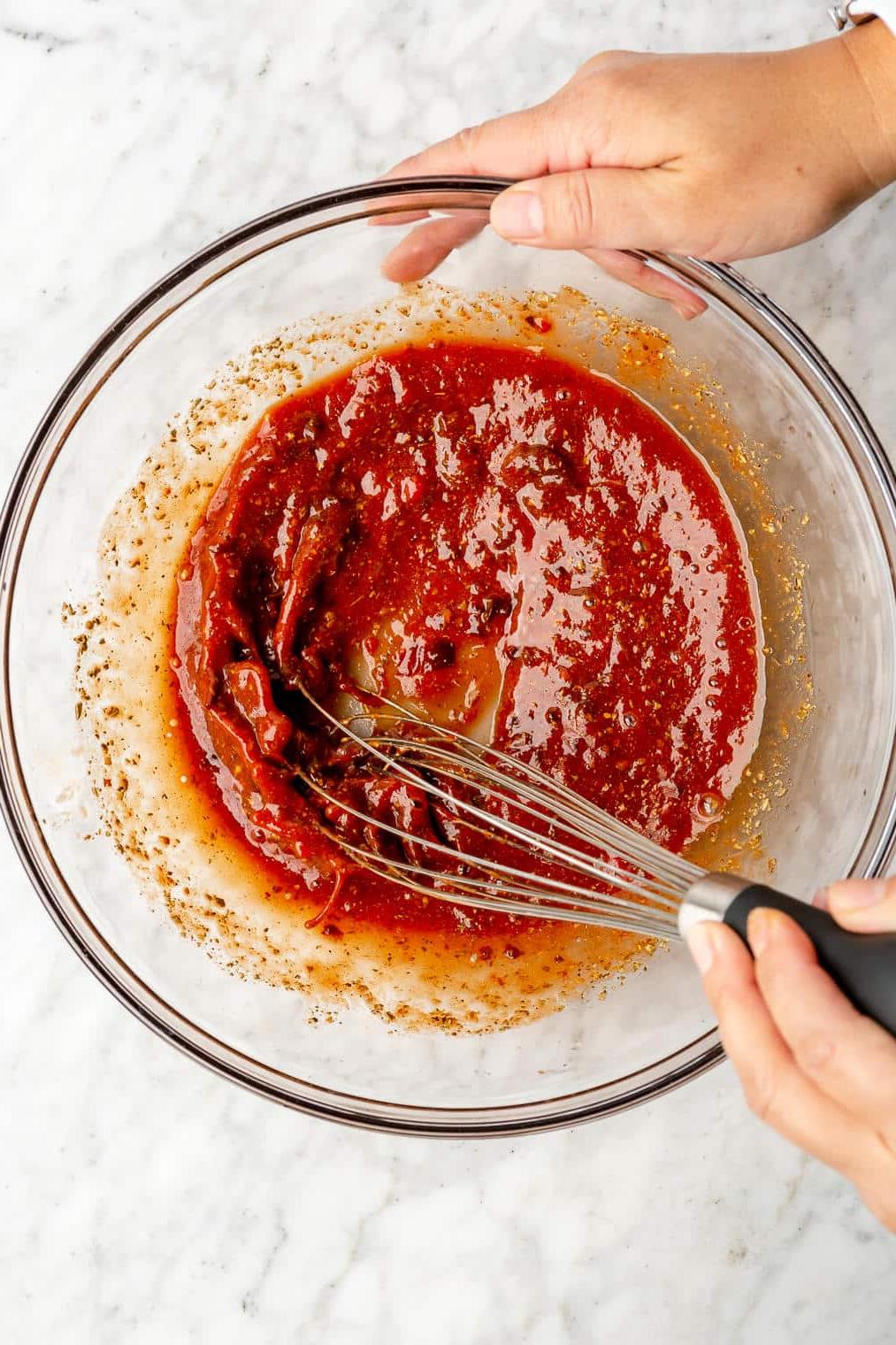 Knusprige Blumenkohl-Tinga-Tacos 4 Eine Person verrührt eine leuchtend rote Tinga-Sauce für Blumenkohl-Tinga-Tacos.
