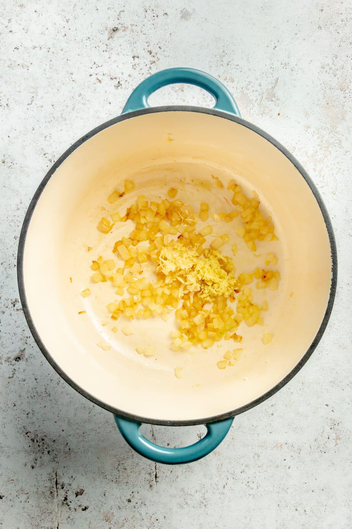 Thailändische Karotten-Ingwer-Suppe 4 Angebratene Zwiebeln, Knoblauch und Ingwer in einem großen emaillierten Gusseisentopf.