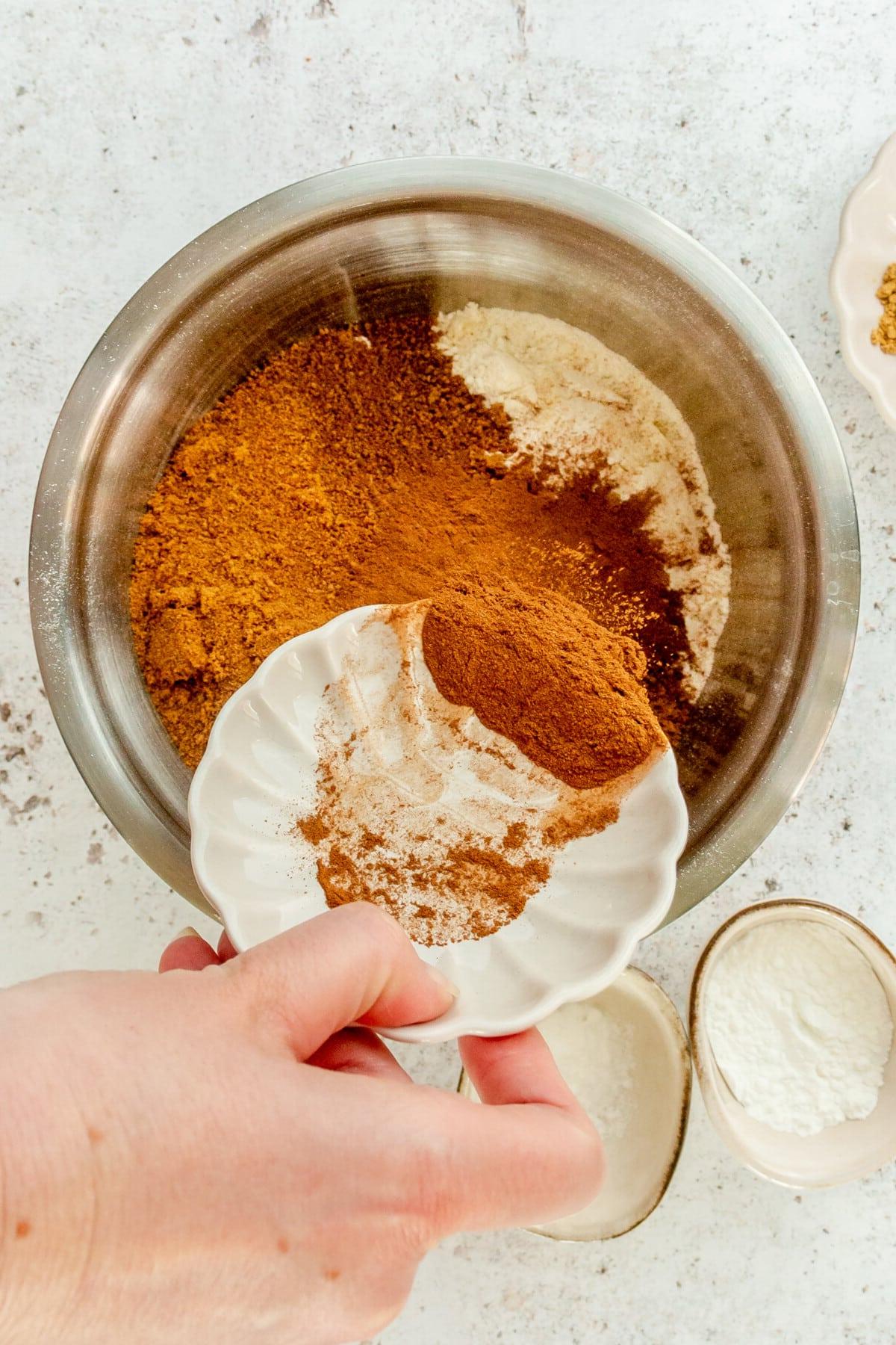 **Paläo Apfel-Zimt-Muffins** 4 Ground cinnamon is tossed into a stainless steel bowl on a light grey surface.