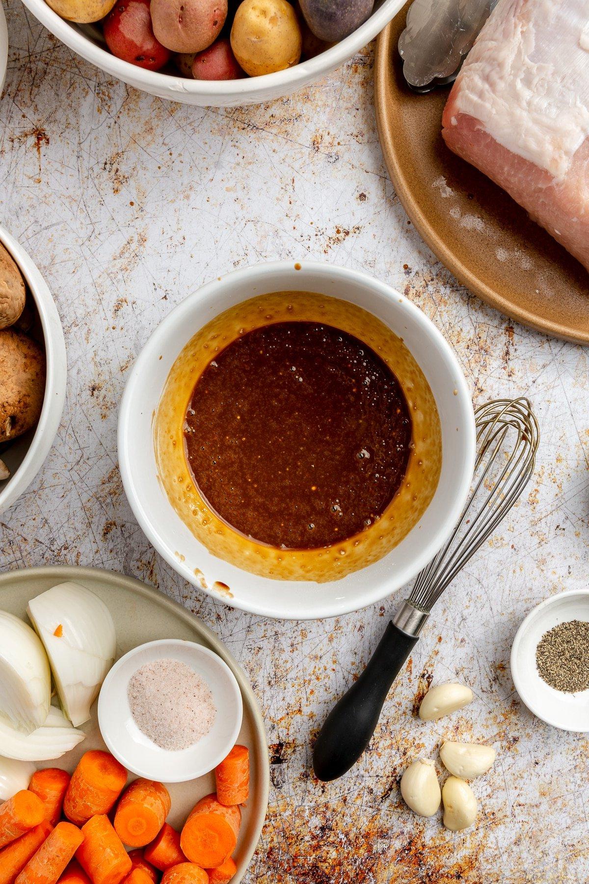 **Balsamico-Schweinelendenrezept** 4 Die dunkelbraune Sauce und das Pulver wurden zu einer goldbraunen Mischung verquirlt. Ein jetzt schmutziger schwarzer Schneebesen liegt daneben.
