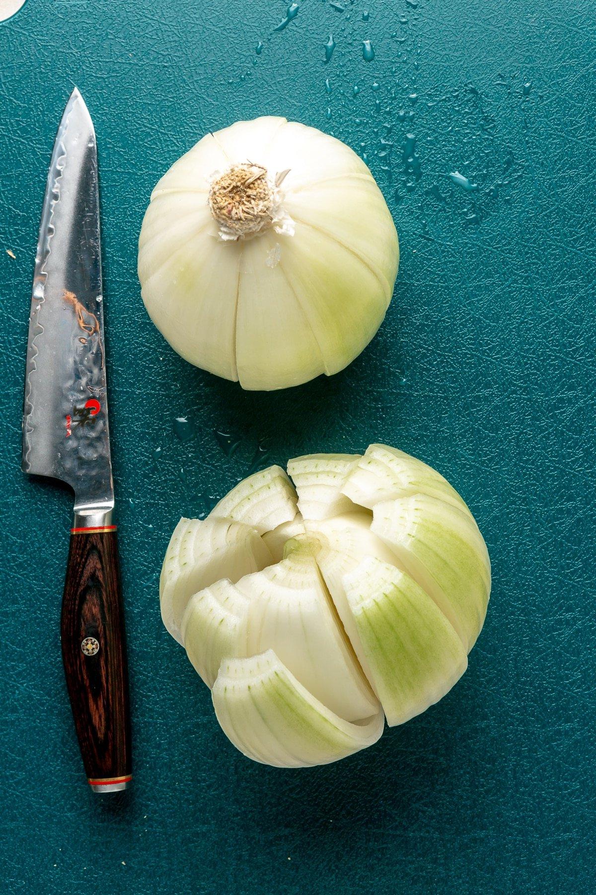 Heißluftfritteuse Blühende Zwiebel 4 Schritt 1: Das obere Stielende der Zwiebel wird abgeschnitten und der innere Kern mit einem Messer vorsichtig entfernt, um Platz für die Blüte zu schaffen.