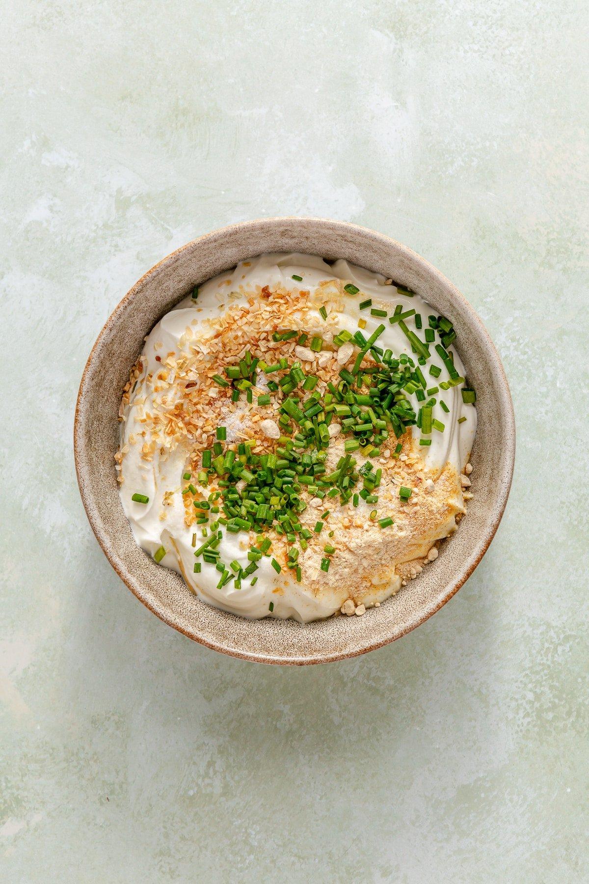 Eine Schüssel mit griechischem Joghurt, Sauerrahm und allen Gewürzen, die für hausgemachten Französischen Zwiebeldip benötigt werden.