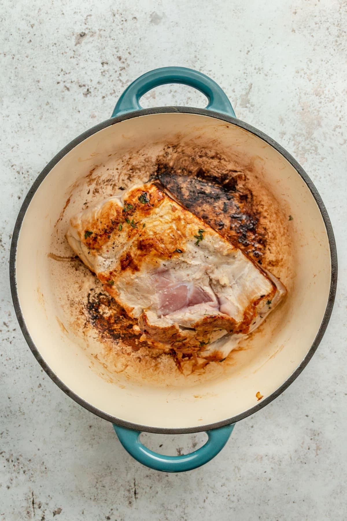 Apfelwein-Schweinebraten 5 Ein angebratenes Schweinefilet liegt in einem Bräter auf einer hellgrauen Oberfläche.