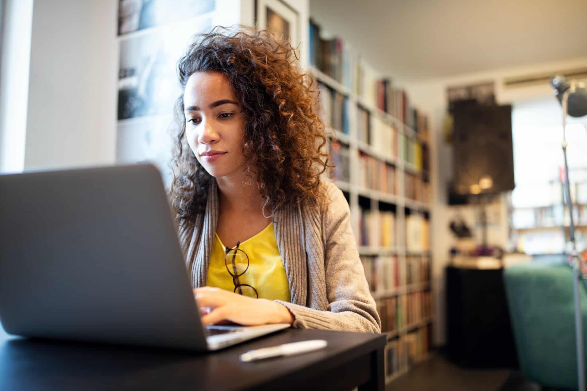 10 Tipps, um im Home-Office gesund zu bleiben 5 woman working at her laptop with bookshelves in the background