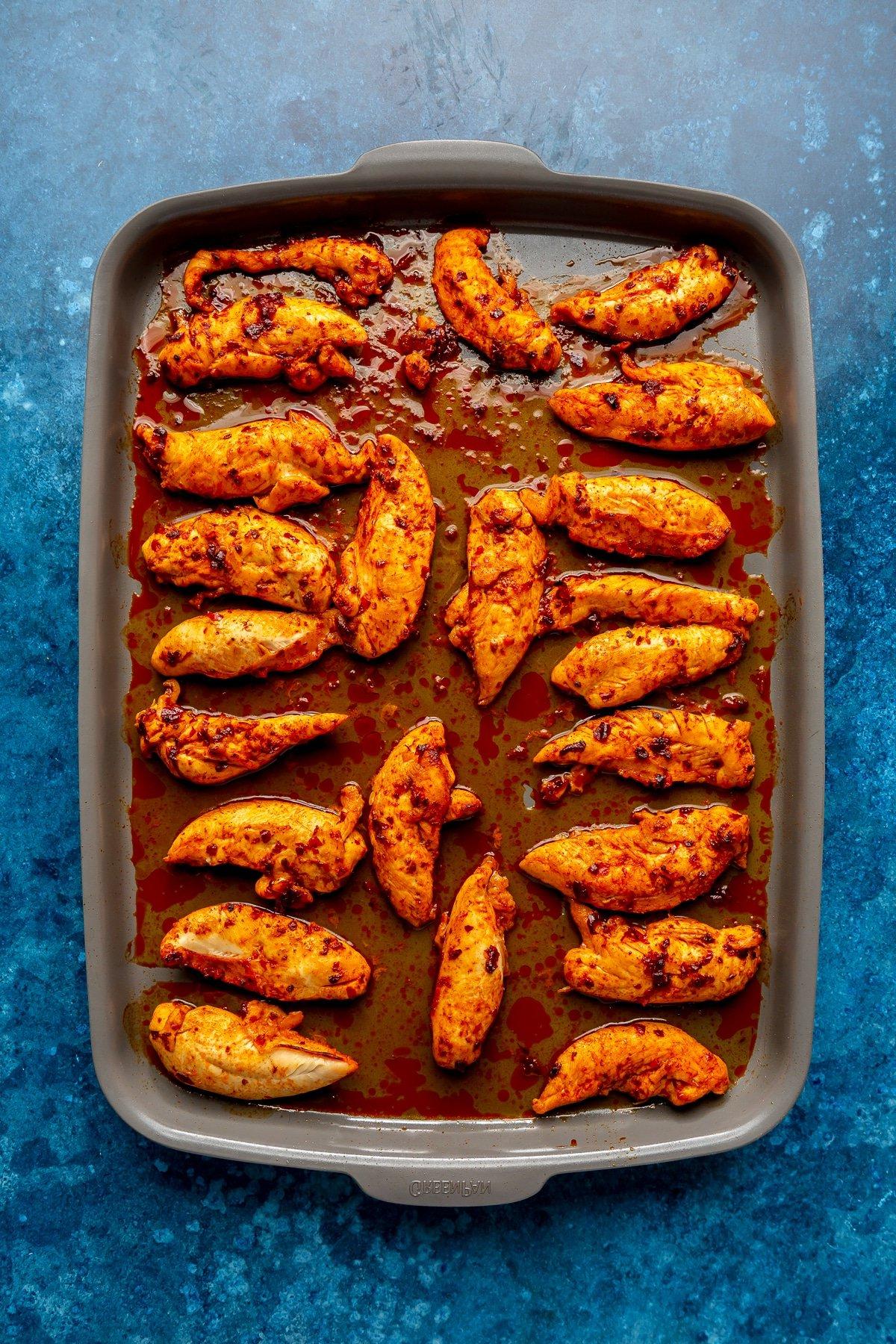 Harissa-Honig-Hähnchen-Bowls 5 Vollständig gebackene Hähnchenstücke liegen auf einem Metallblech.