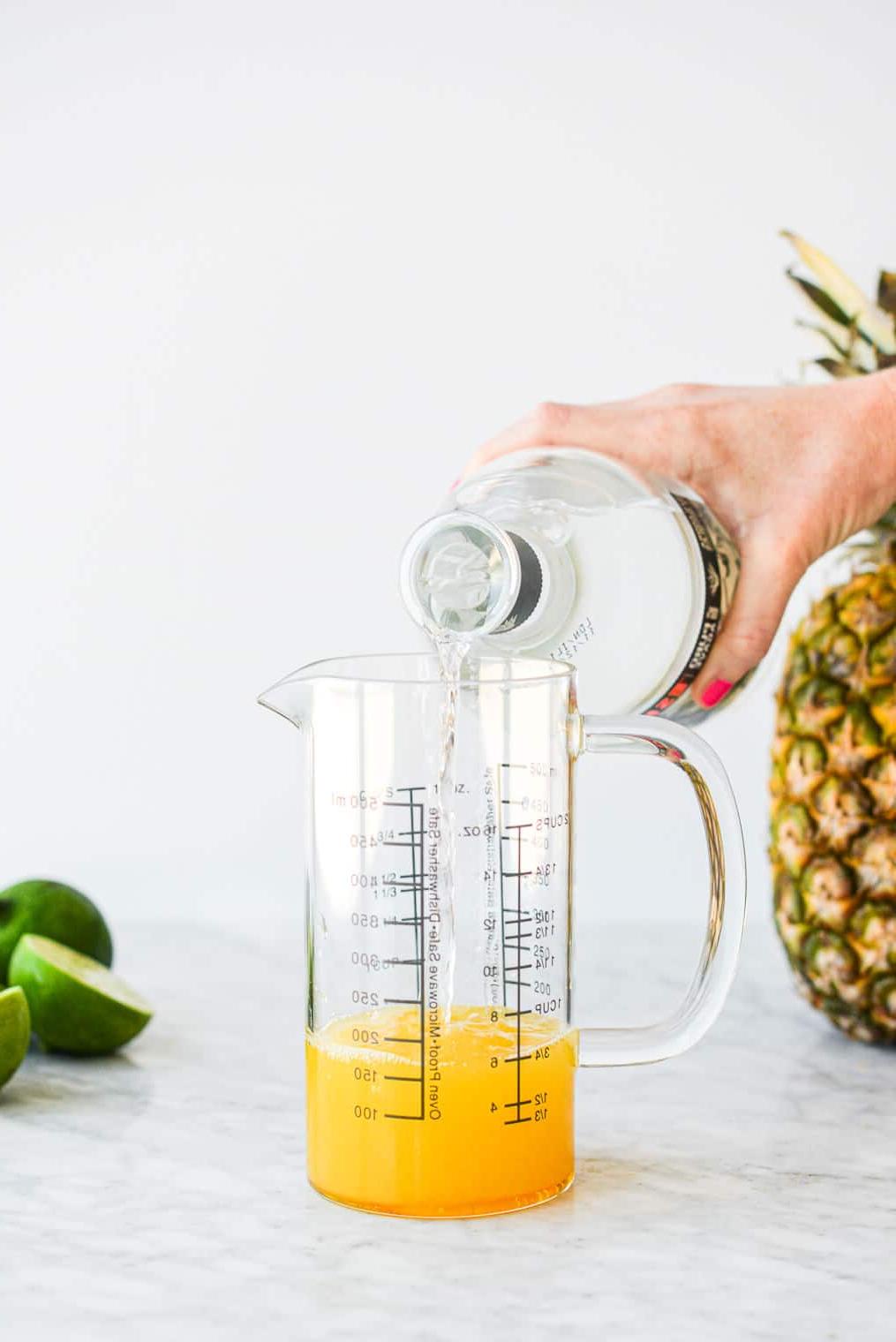 210614_Pineapple Margarita-12 Eine Person gießt Tequila in einen großen Messbecher aus Glas.