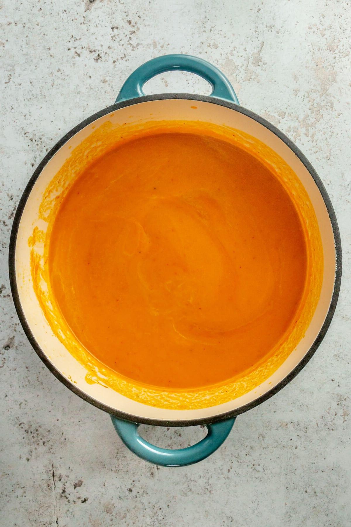 Thailändische Karotten-Ingwer-Suppe 6 Pürierte, glatte Karottensuppe in einem blauen emaillierten Gusseisentopf.