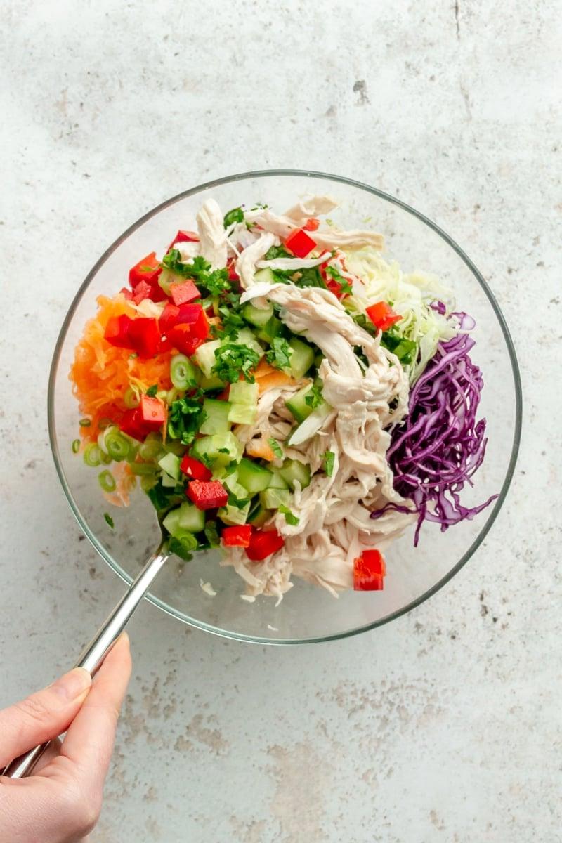 Thai-inspirierter Erdnuss-Hähnchensalat 6 Zutaten für den Thai-inspirierten Hähnchensalat werden in einer Glasschüssel vermischt.