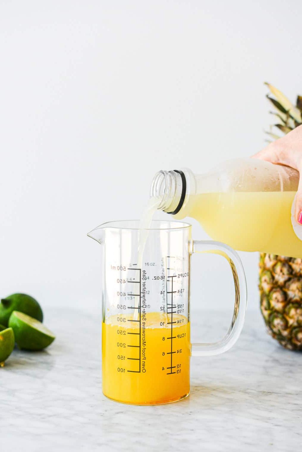 210614_Pineapple Margarita-10 Eine Person gießt Limettensaft zusammen mit den anderen Ananas Margarita Zutaten in einen großen Messbecher aus Glas.