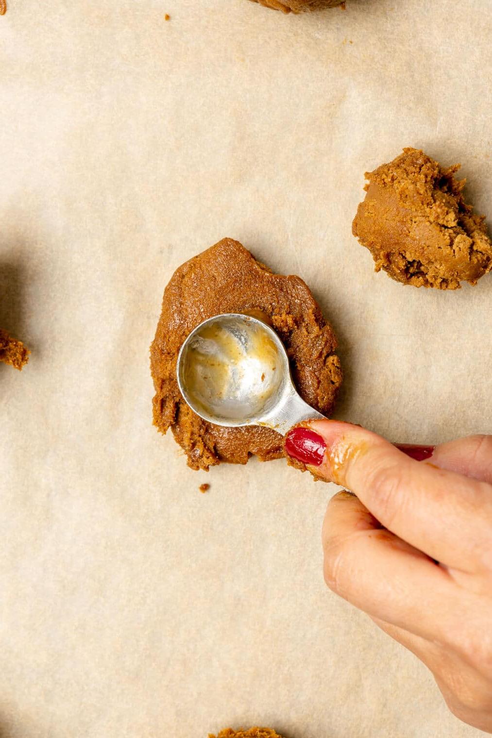 220817_Rum Raisin Cookies-40 Hand macht eine Vertiefung in Keksteig mit einem Messlöffel.