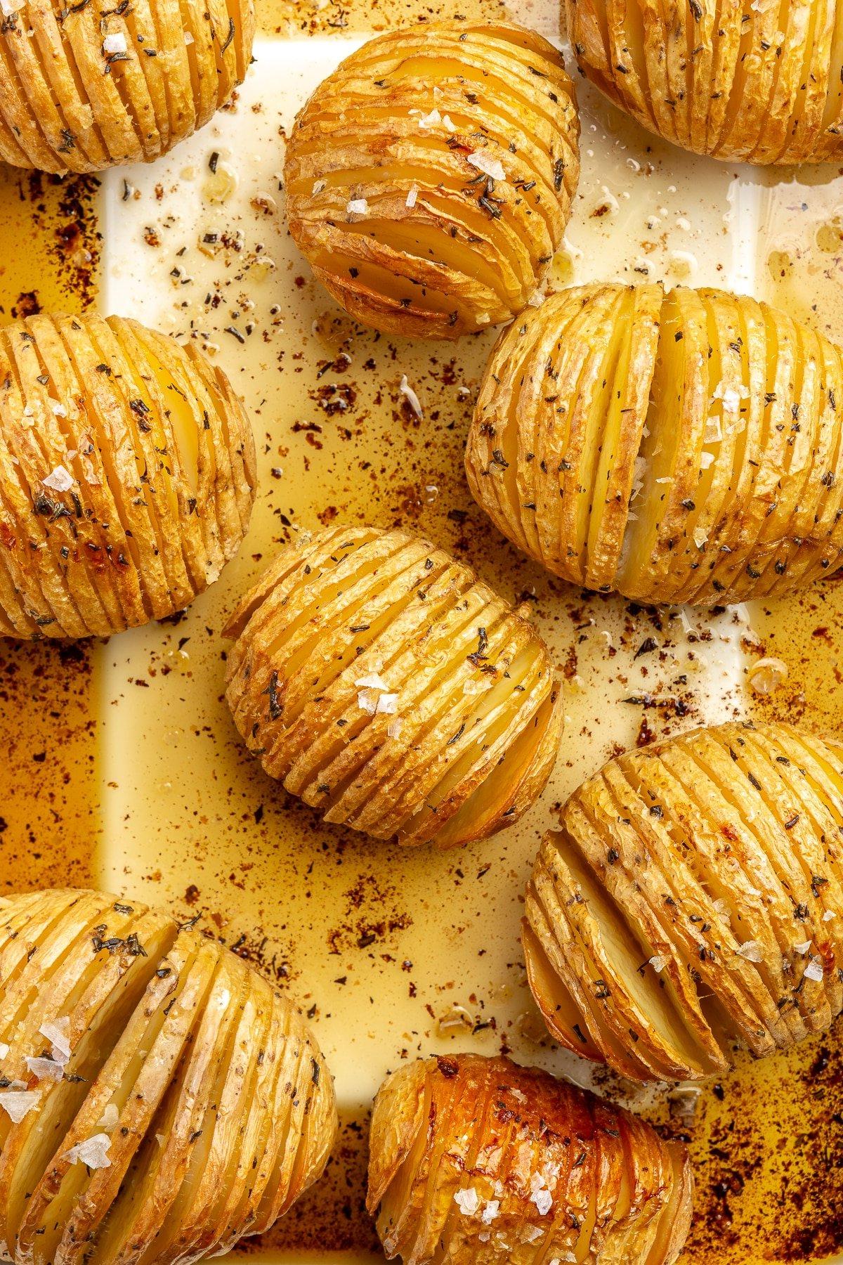 Hasselback-Kartoffeln mit Rosmarin 8 Fertig gebackene, goldbraune Kartoffeln liegen auf einem Backblech. Grobes Salz ist darüber gestreut.