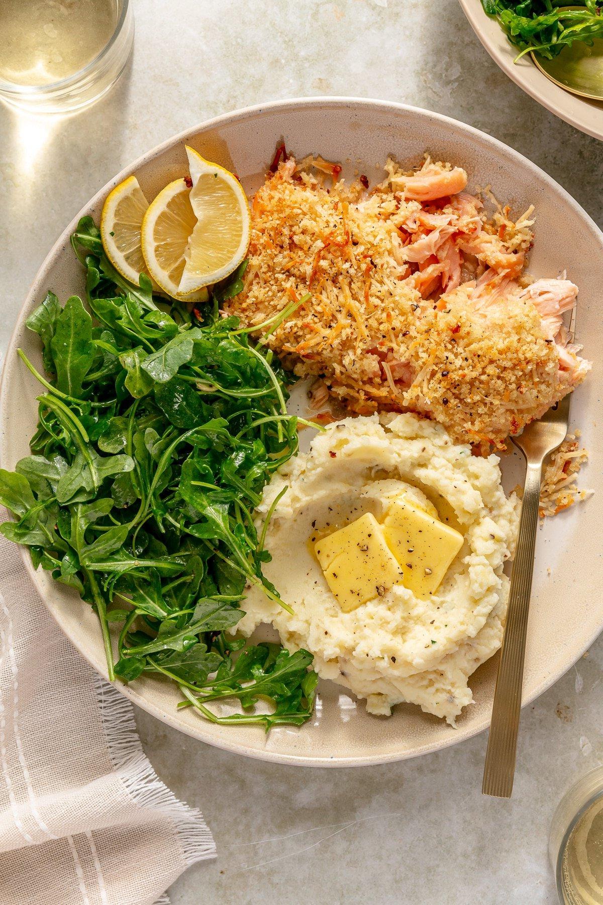 Lachs mit Parmesankruste 8 Ein kunstvoll angerichteter Teller mit Parmesan-Lachs, frischer Petersilie und Zitronenspalten, bereit zum Verzehr.