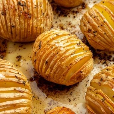 Hasselback-Kartoffeln mit Rosmarin 9 Fertig gebackene, goldbraune Kartoffeln liegen auf einem Backblech. Grobes Salz ist darüber gestreut.