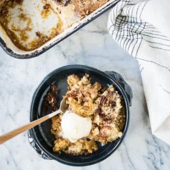 Kürbis-Dump-Kuchen 9 Dunkelblaue Schüssel mit Kürbis-Dump-Cake und einer Kugel Eiscreme darauf.