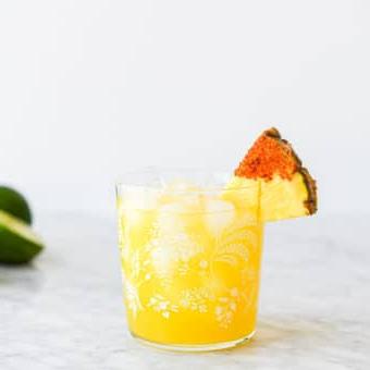 Die beste Ananas-Margarita (2 Varianten!) 4 Ein Margarita-Glas mit einem Ananas Margarita auf Eis, garniert mit einem in Chili-Salz getauchten Ananas-Keil.