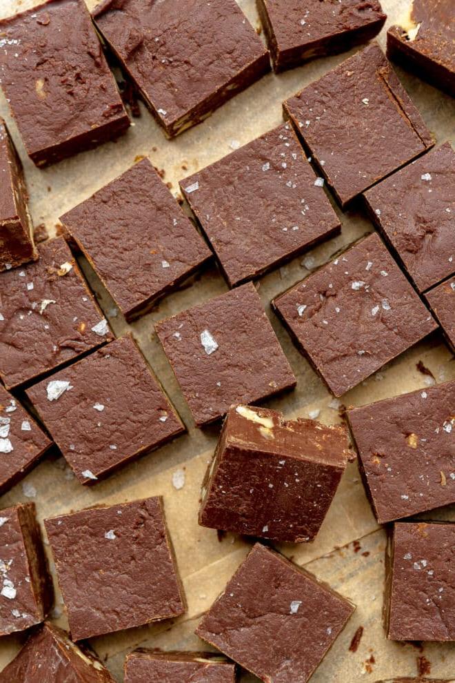Kleine Quadrate aus Schokoladenfudge auf einem braunen Stück Backpapier.