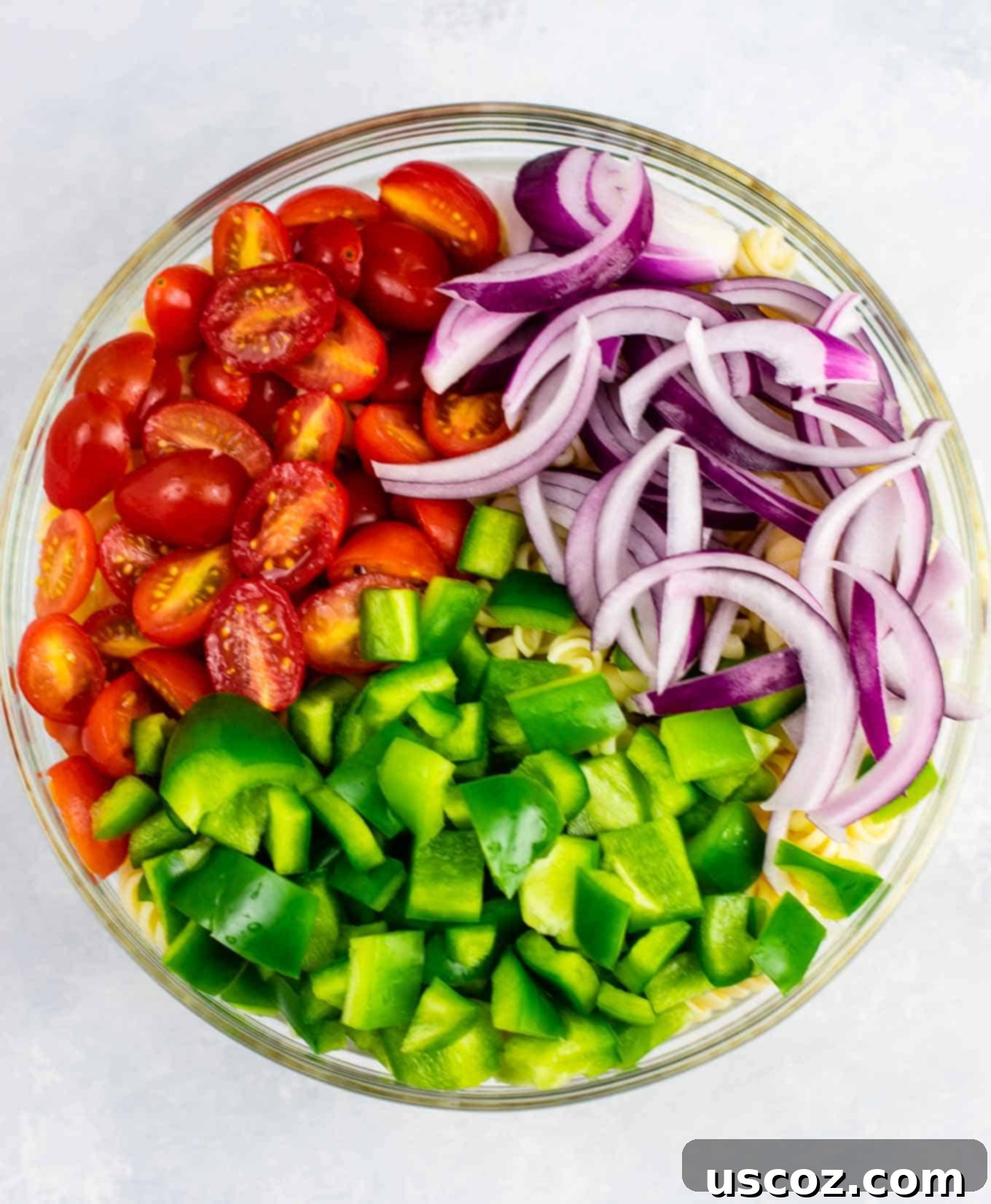 Vegan Pasta Salad 4 Freshly chopped red onion, green bell pepper, and halved cherry tomatoes, ready to be added to the vegan pasta salad.