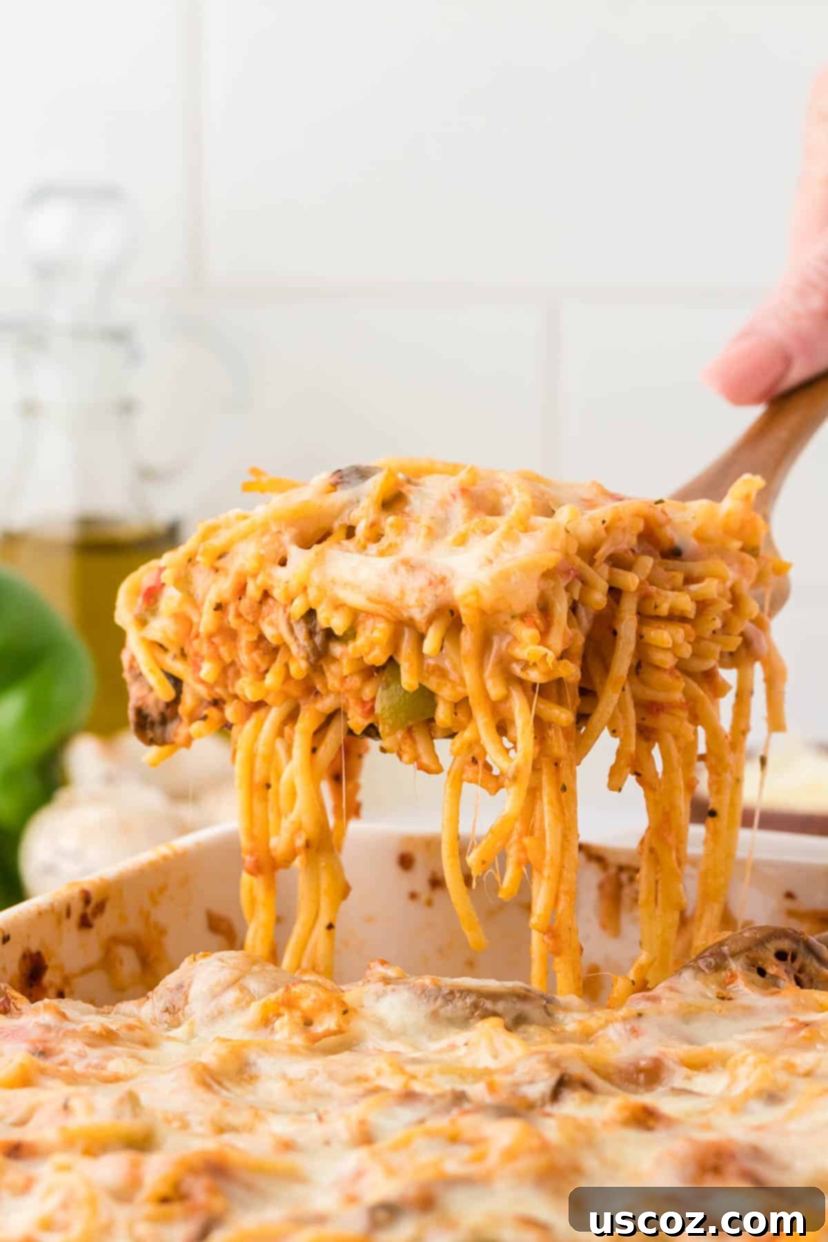 Hearty Vegetarian Spaghetti Bake 23 A hand scooping a generous portion of vegetarian baked spaghetti from a casserole dish
