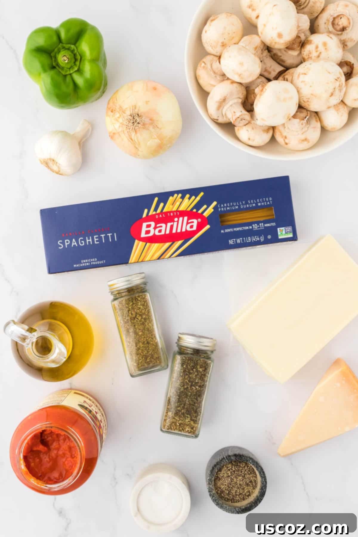Hearty Vegetarian Spaghetti Bake 4 Fresh ingredients laid out on a wooden surface: chopped mushrooms, onion, bell pepper, garlic, olive oil, spices, pasta sauce, and two types of cheese