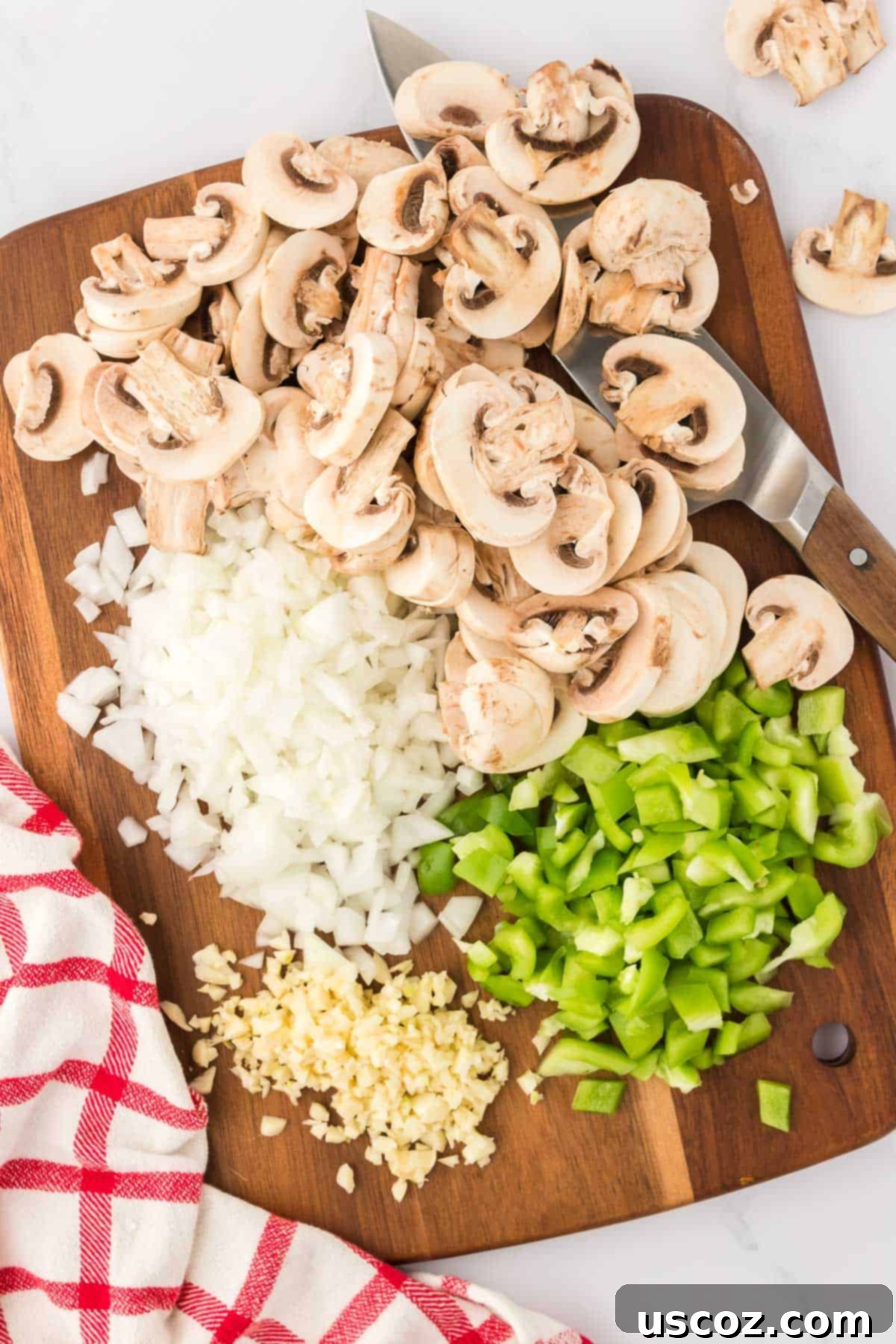 Hearty Vegetarian Spaghetti Bake 5 Freshly chopped mushrooms, diced onion, minced garlic, and green bell pepper arranged neatly on a cutting board, ready for cooking