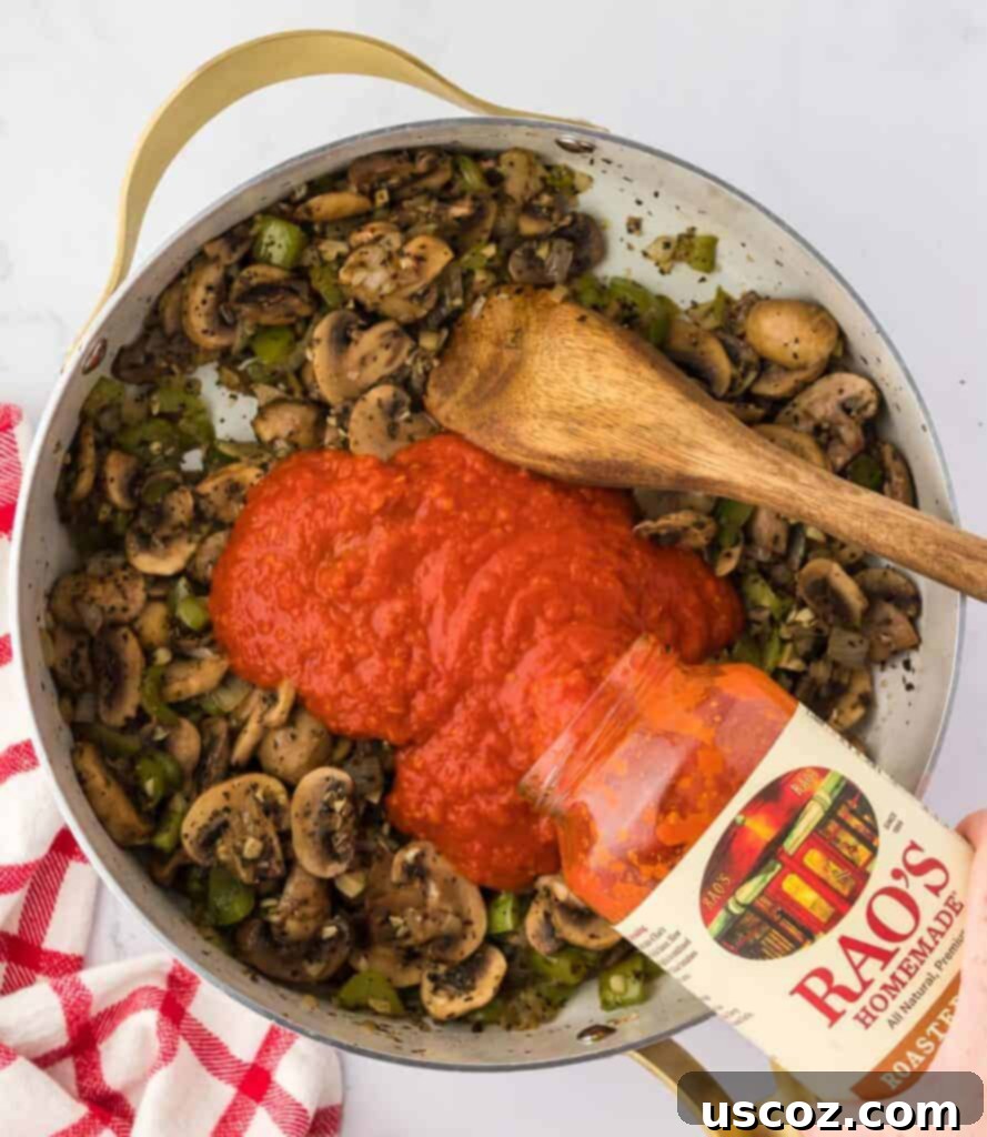 Hearty Vegetarian Spaghetti Bake 9 Pouring jarred pasta sauce over sautéed vegetables in a large skillet