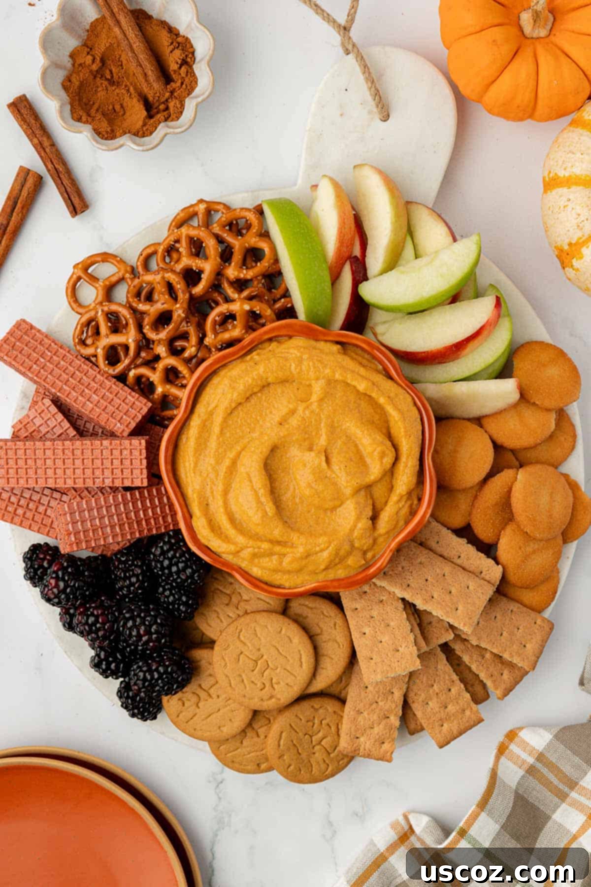 Pumpkin Cheesecake Dip 2 pumpkin dip on a board surrounded with crackers, apples, pretzels, and fruit