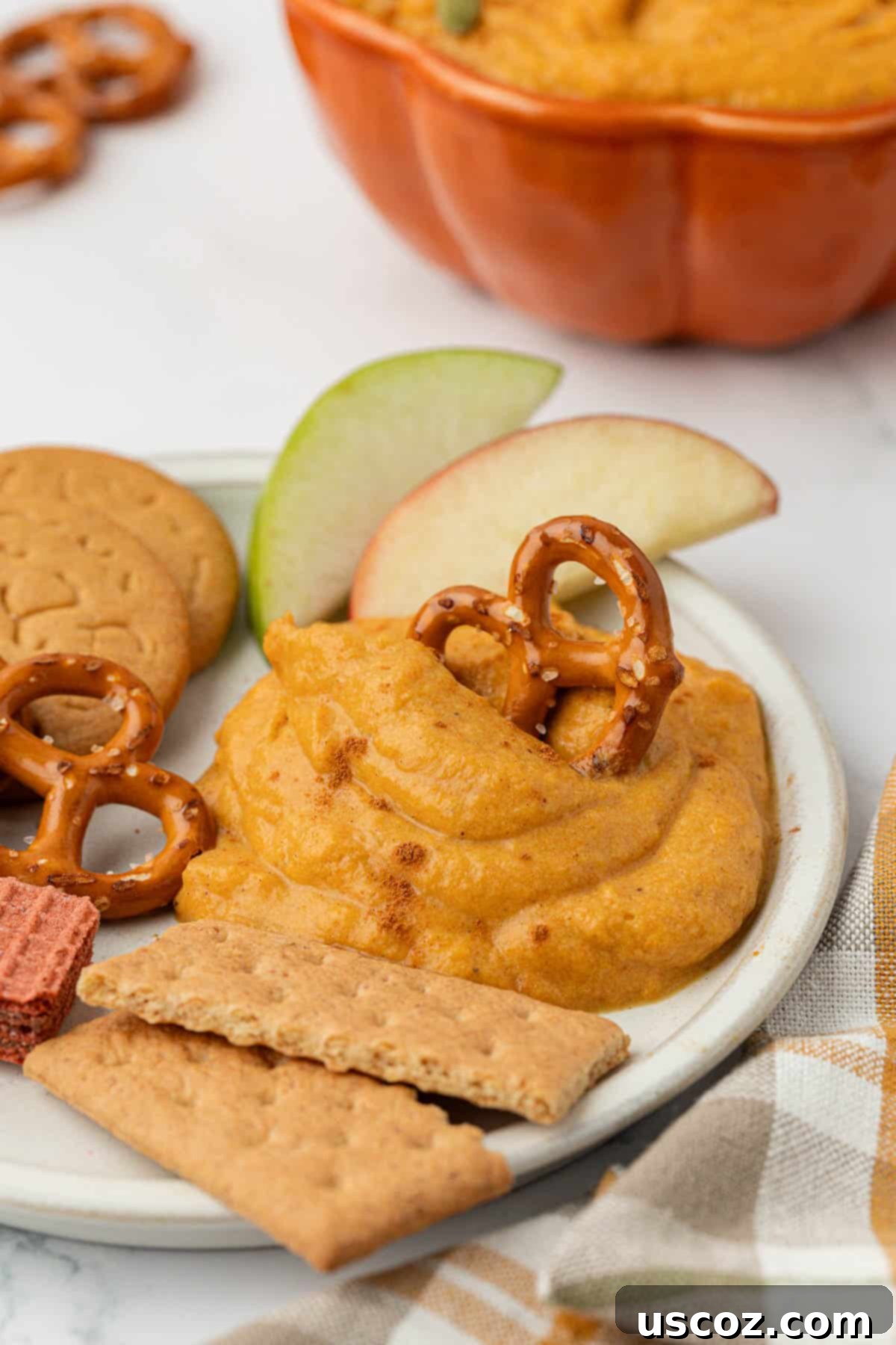 Pumpkin Cheesecake Dip 3 pretzel dipped in pumpkin dip on a plate