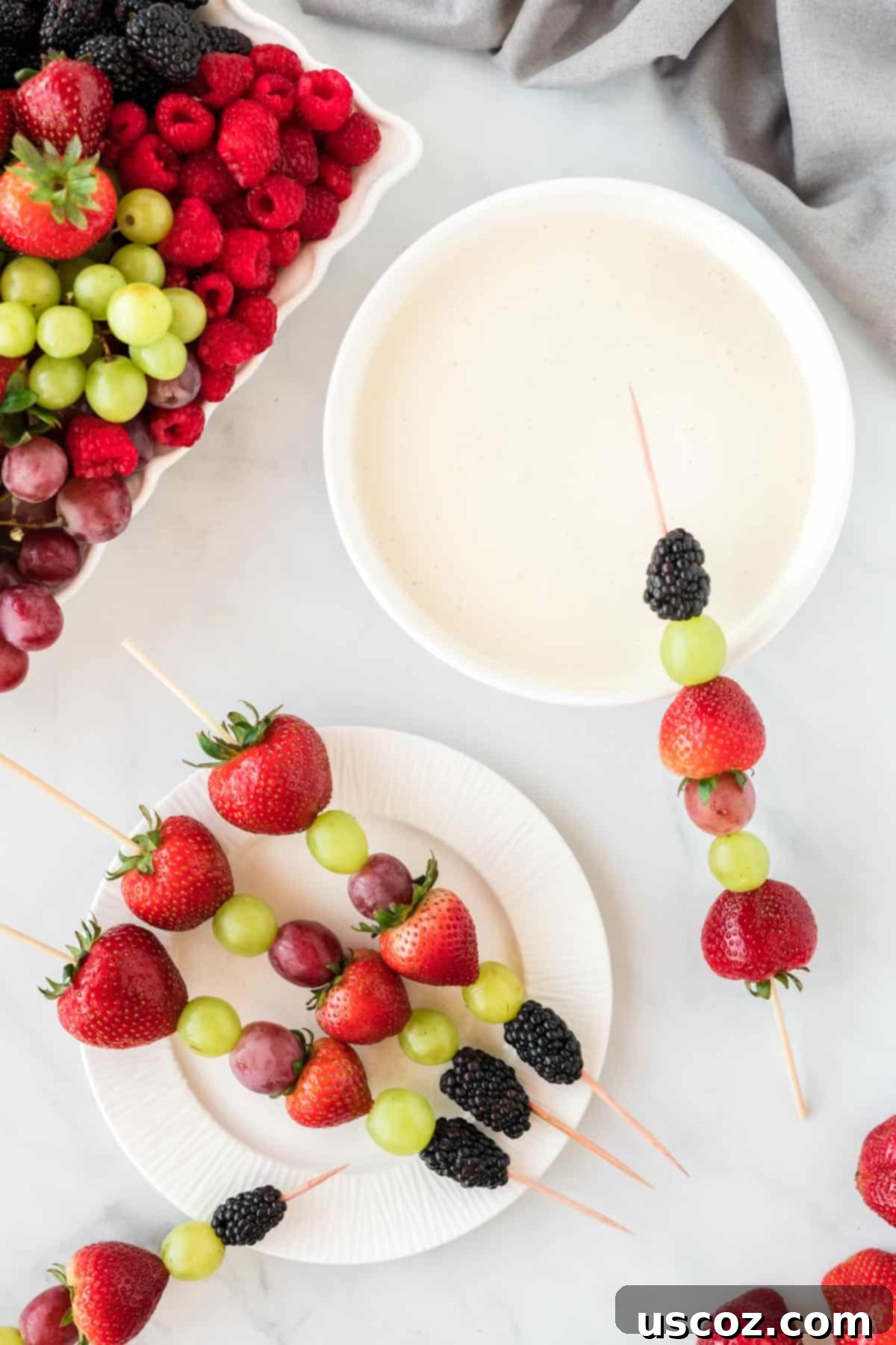 75 Delicious Vegetarian Meals 2 fruit skewers with strawberries, grapes, and blackberries with a bowl of fruit dip