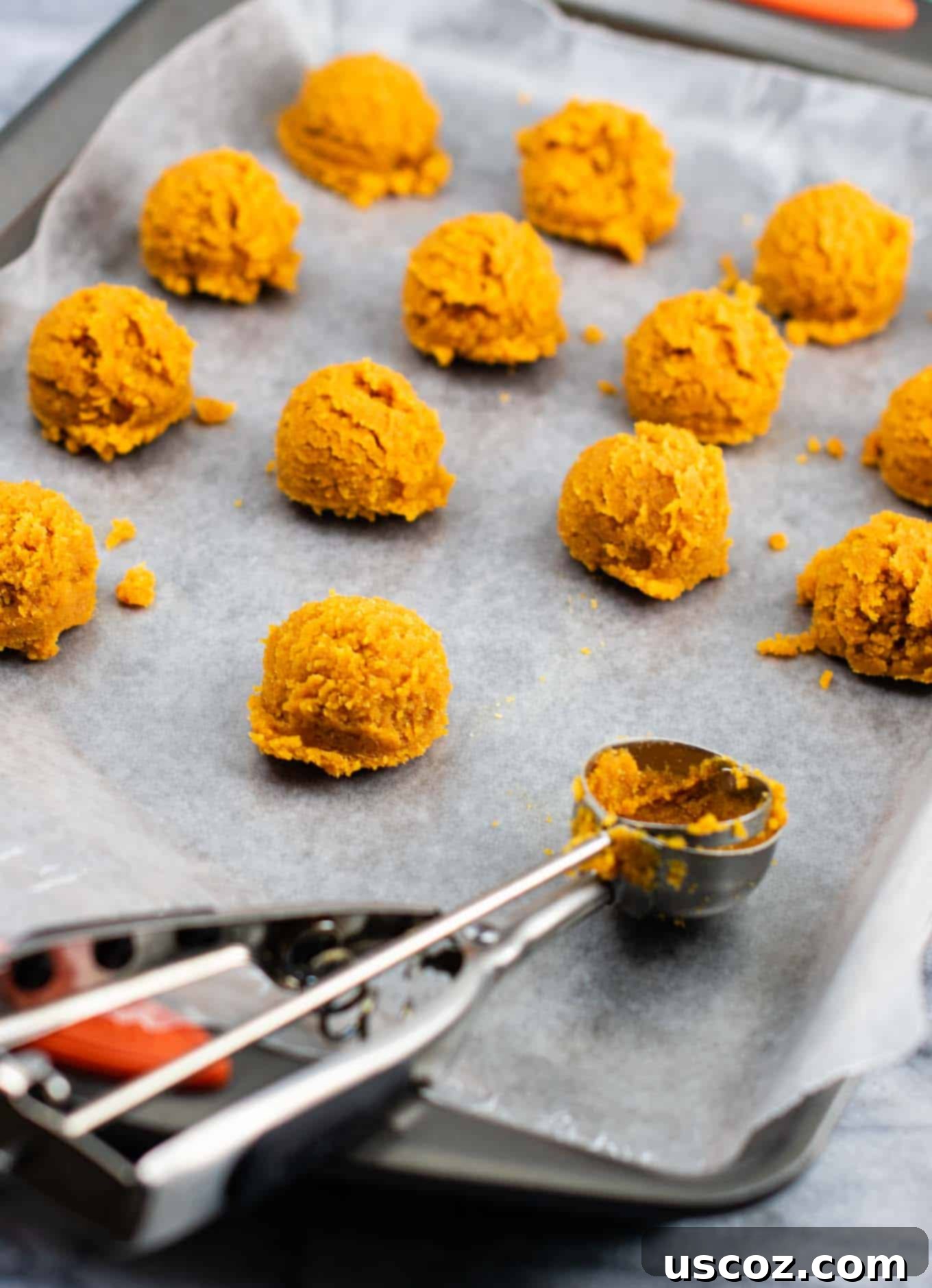 Bittersweet Pumpkin Spice Truffles 4 Scoops of pumpkin truffle dough neatly arranged on a wax paper-lined baking sheet