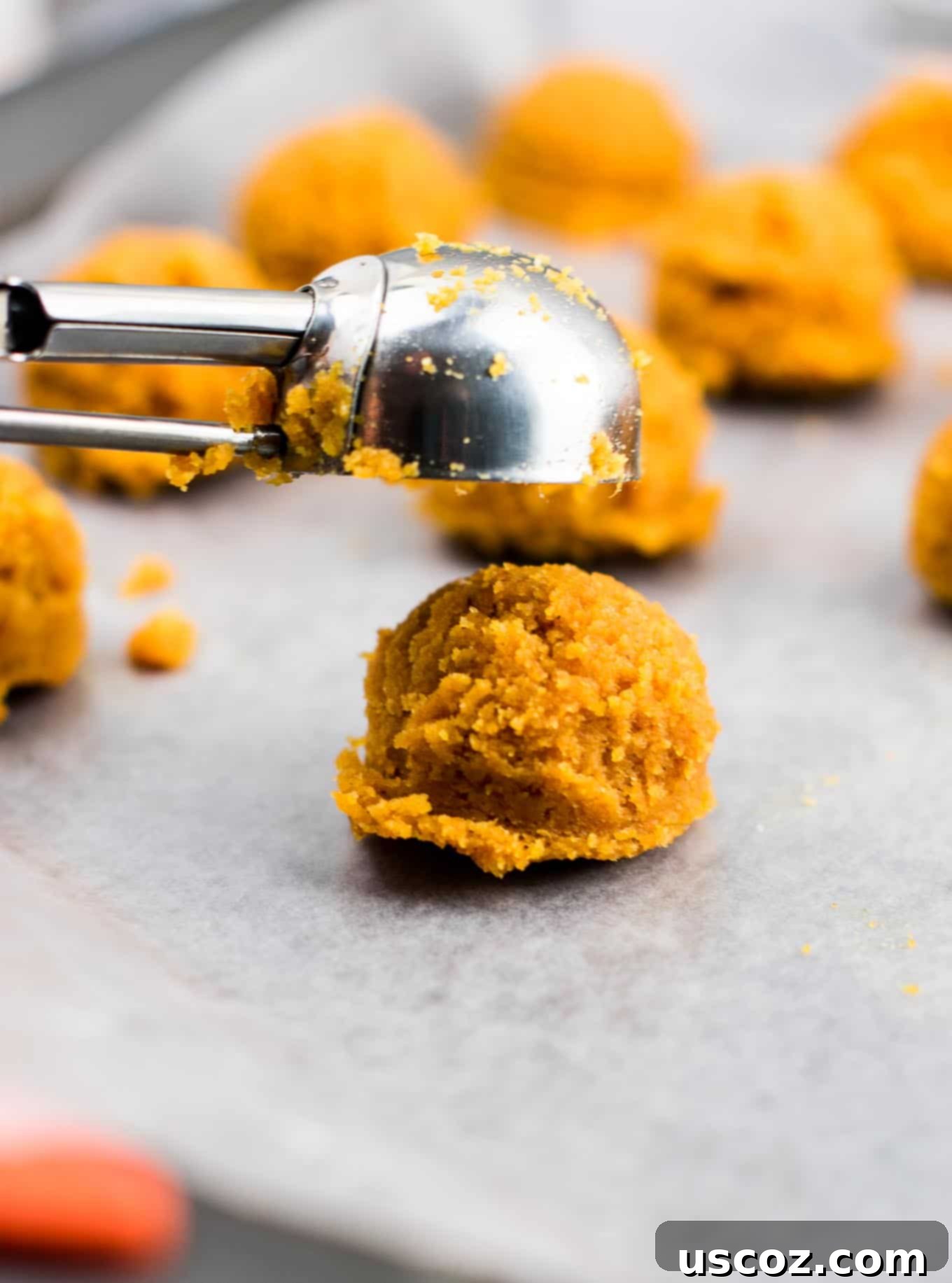Bittersweet Pumpkin Spice Truffles 5 A mini cookie scoop being used to drop truffle dough onto a baking sheet
